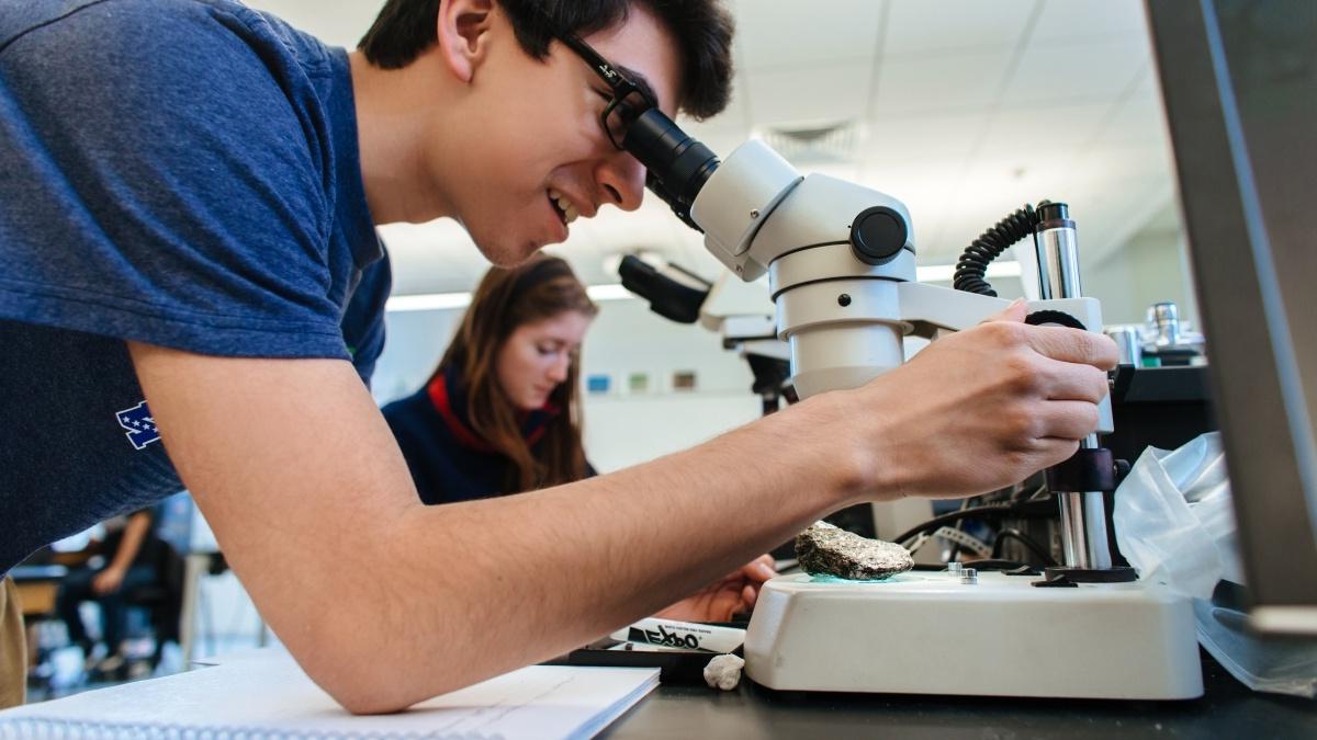 Student looking at rock through a microscope