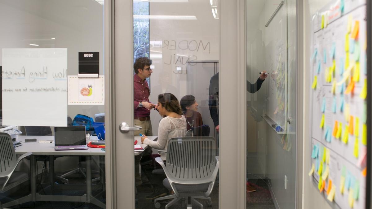 Students brainstorming in a glassed in room.